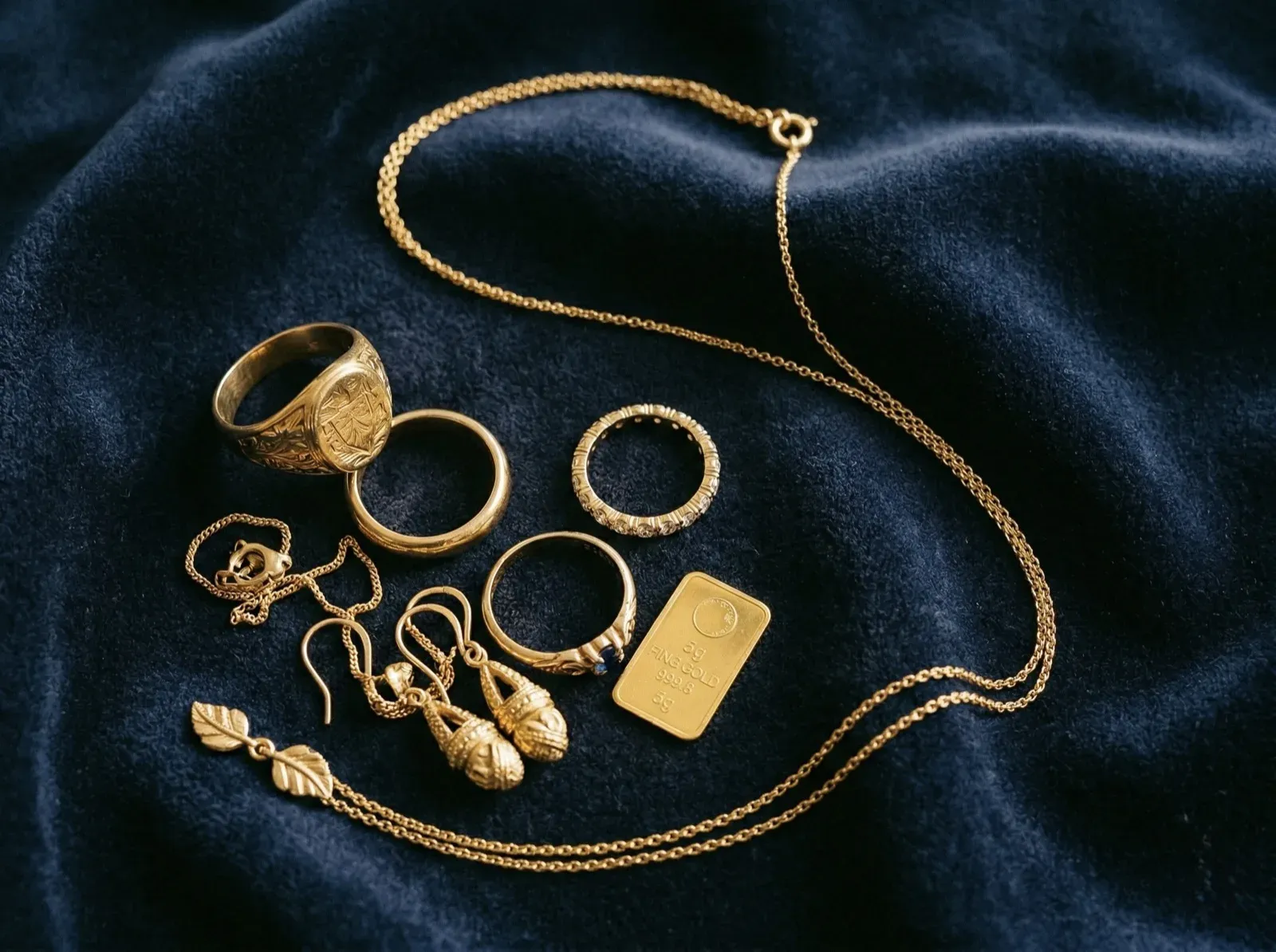 Collection of gold rings, necklace and earrings on dark velvet